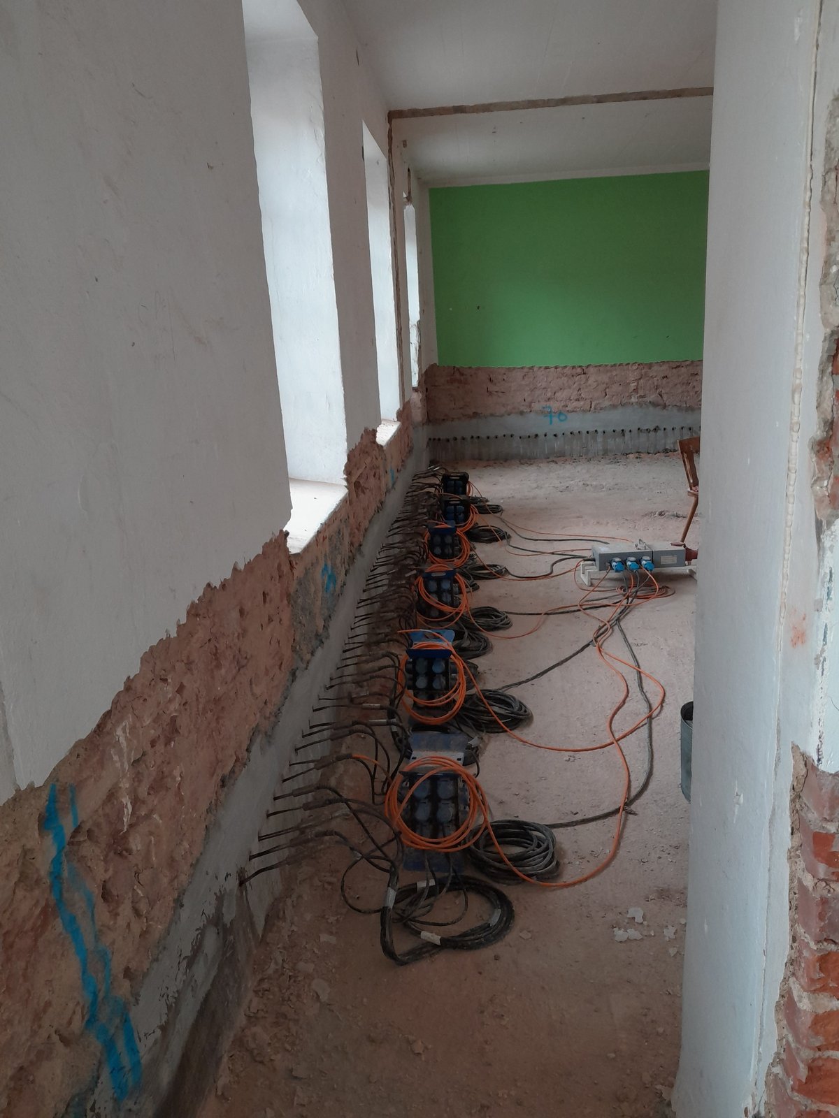 Baugeräte mit Kabeln entlang freigelegter Wand im Raum