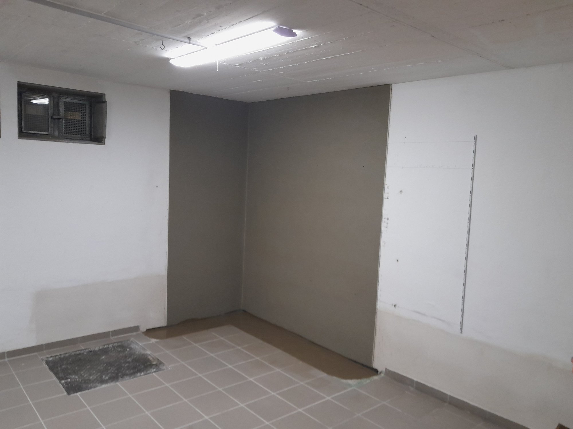 Raumecke mit grauer Wandfläche und hellem Fliesenboden