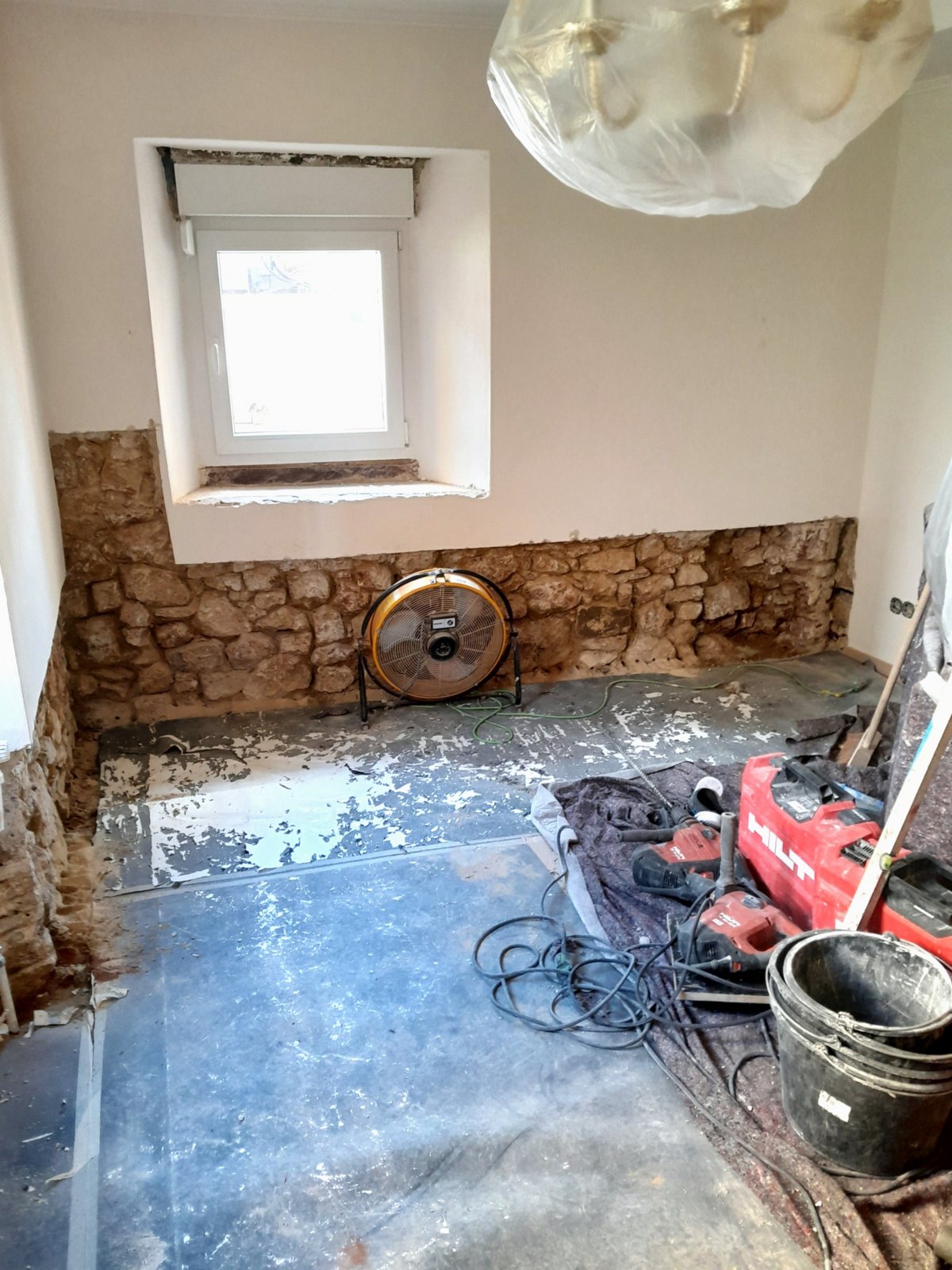 Freigelegte Steinwand in Raum mit Bauwerkzeugen.