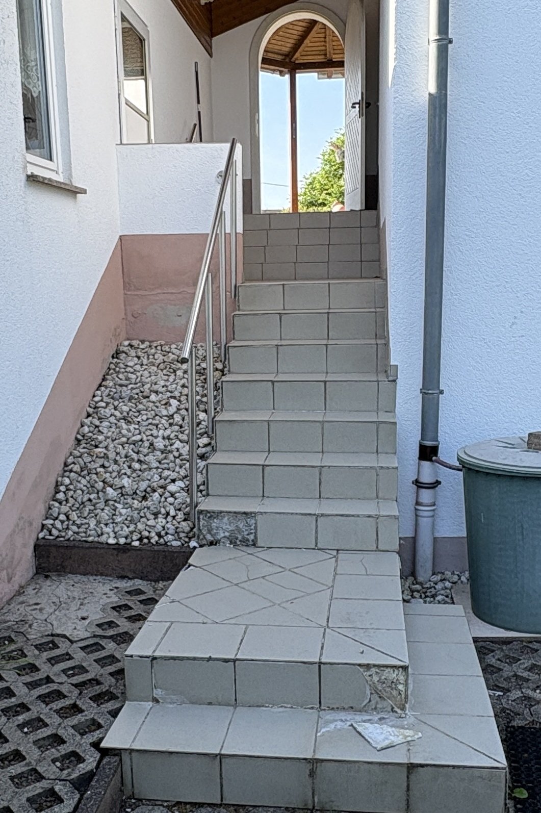 Geflieste Außentreppe mit Edelstahlgeländer an Hauseingang