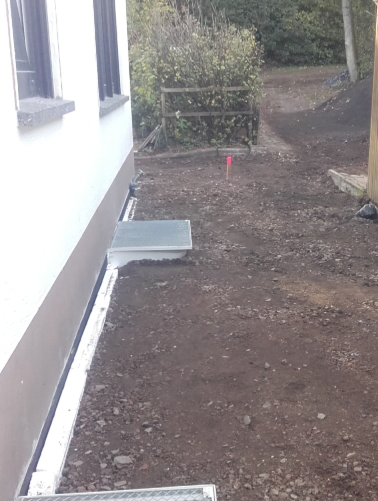 Freigelegter Hausbereich mit Erdreich und zwei Metallabdeckungen.