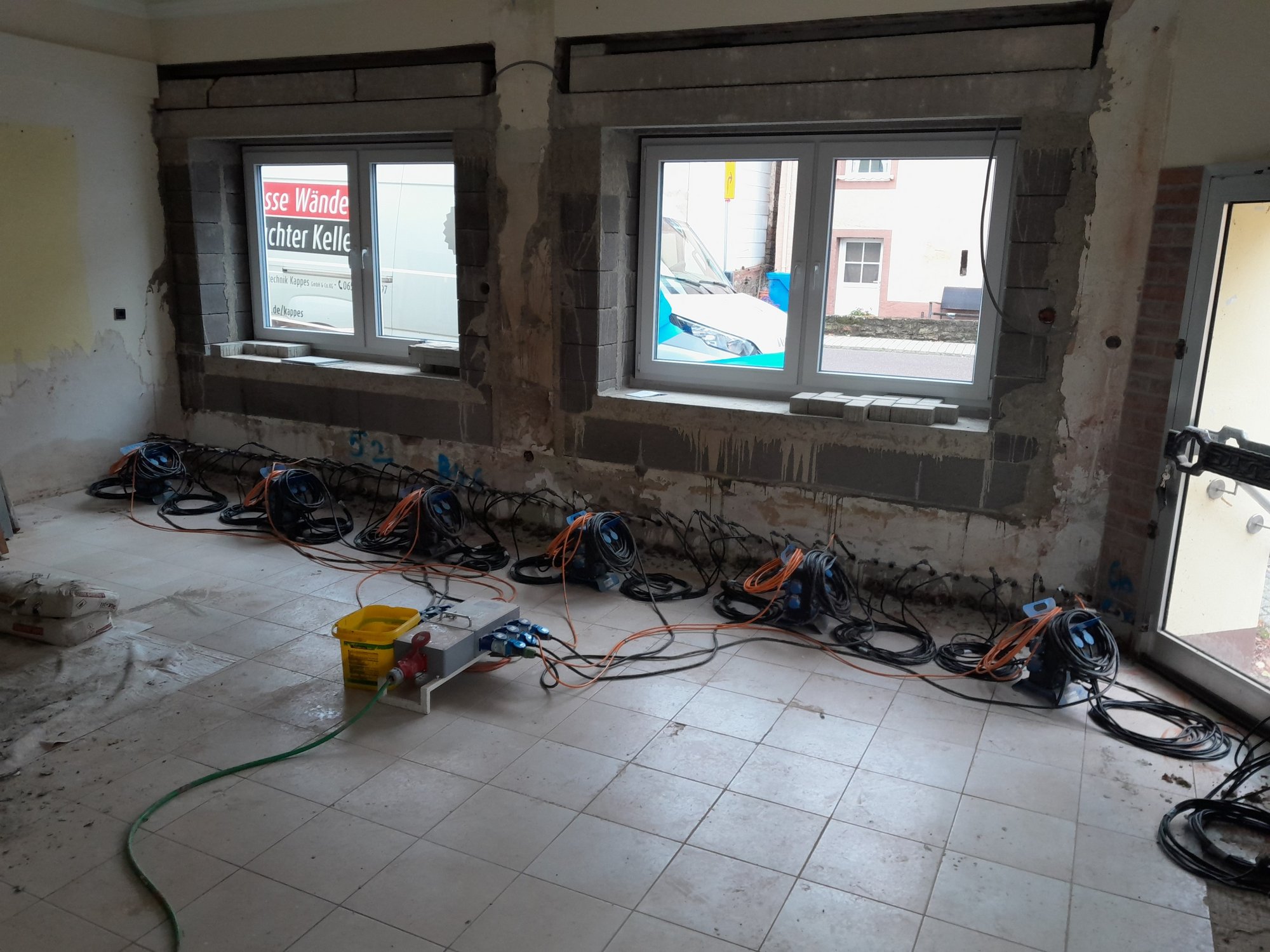 Freigelegte Wand in Raum mit mehreren angeschlossenen Geräten am Boden.