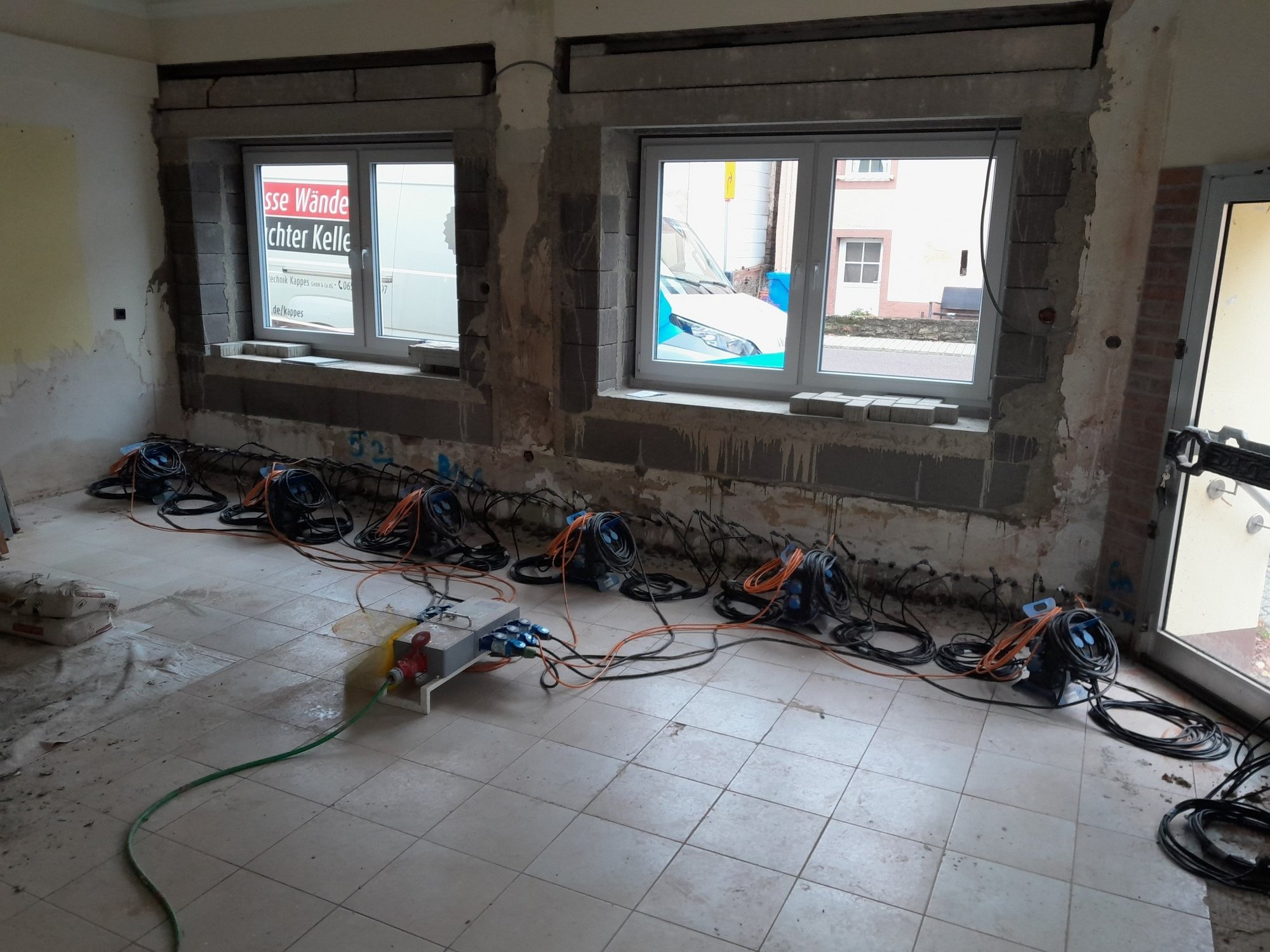 Renovierter Raum mit freigelegter Wand und zahlreichen Geräten am Boden