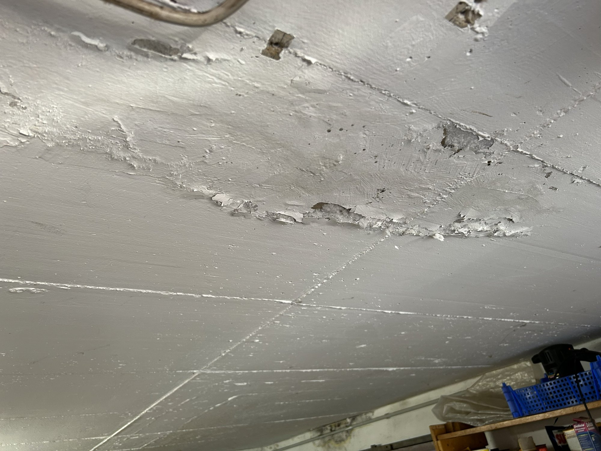 Abgeplatzte Beschichtung an grauer Decke im Innenraum