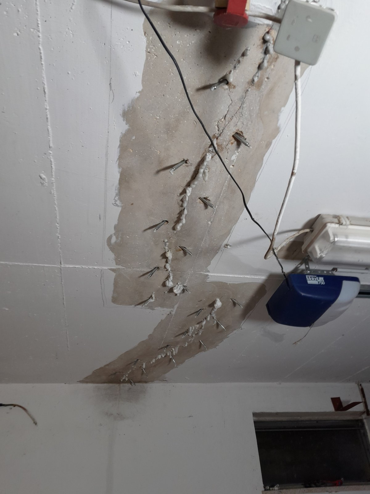 Rissige Deckenfläche mit eingesetzten Düsen und weißer Masse