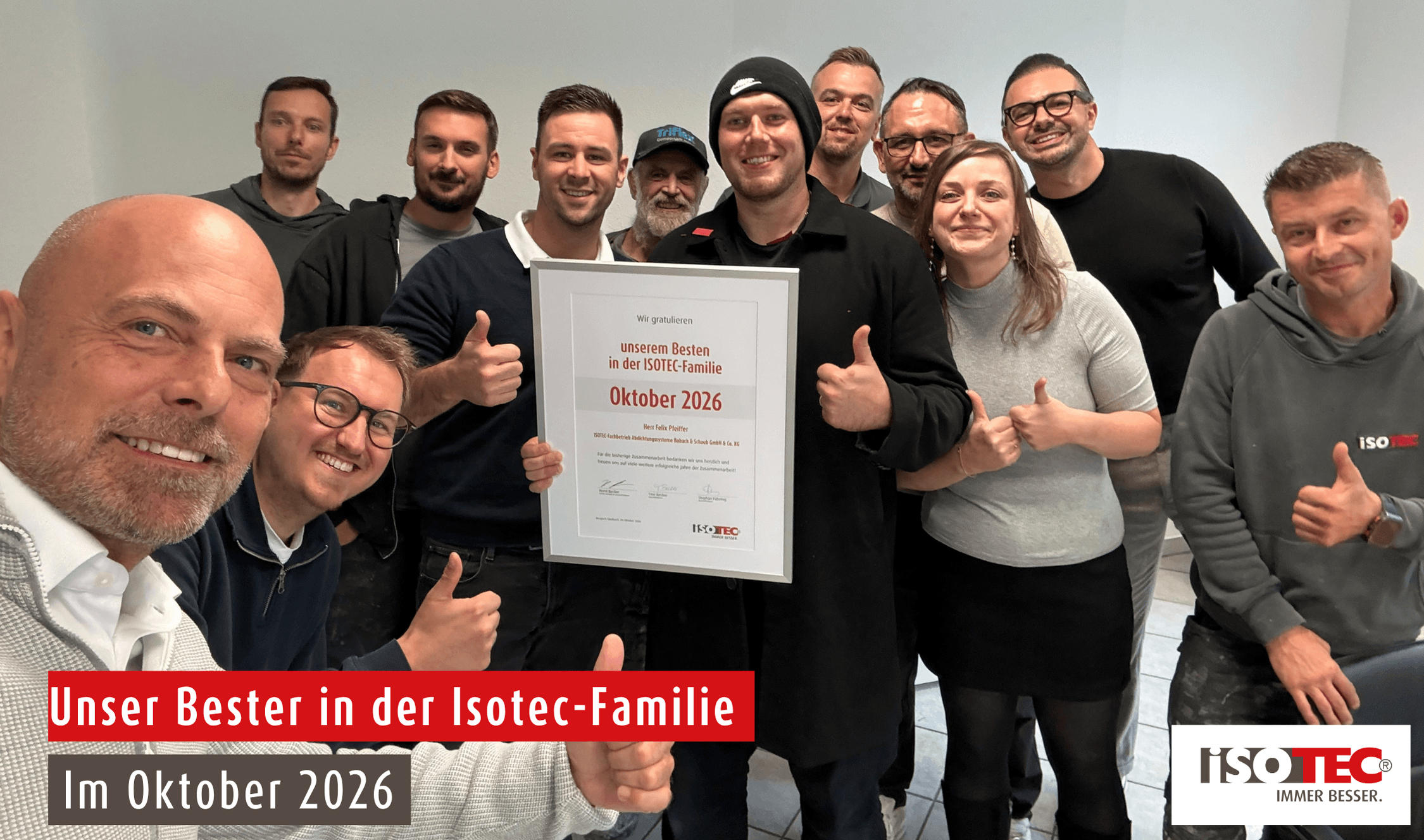 ISOTEC Team hält Urkunde „Oktober 2026“ hoch und zeigt Daumen nach oben
