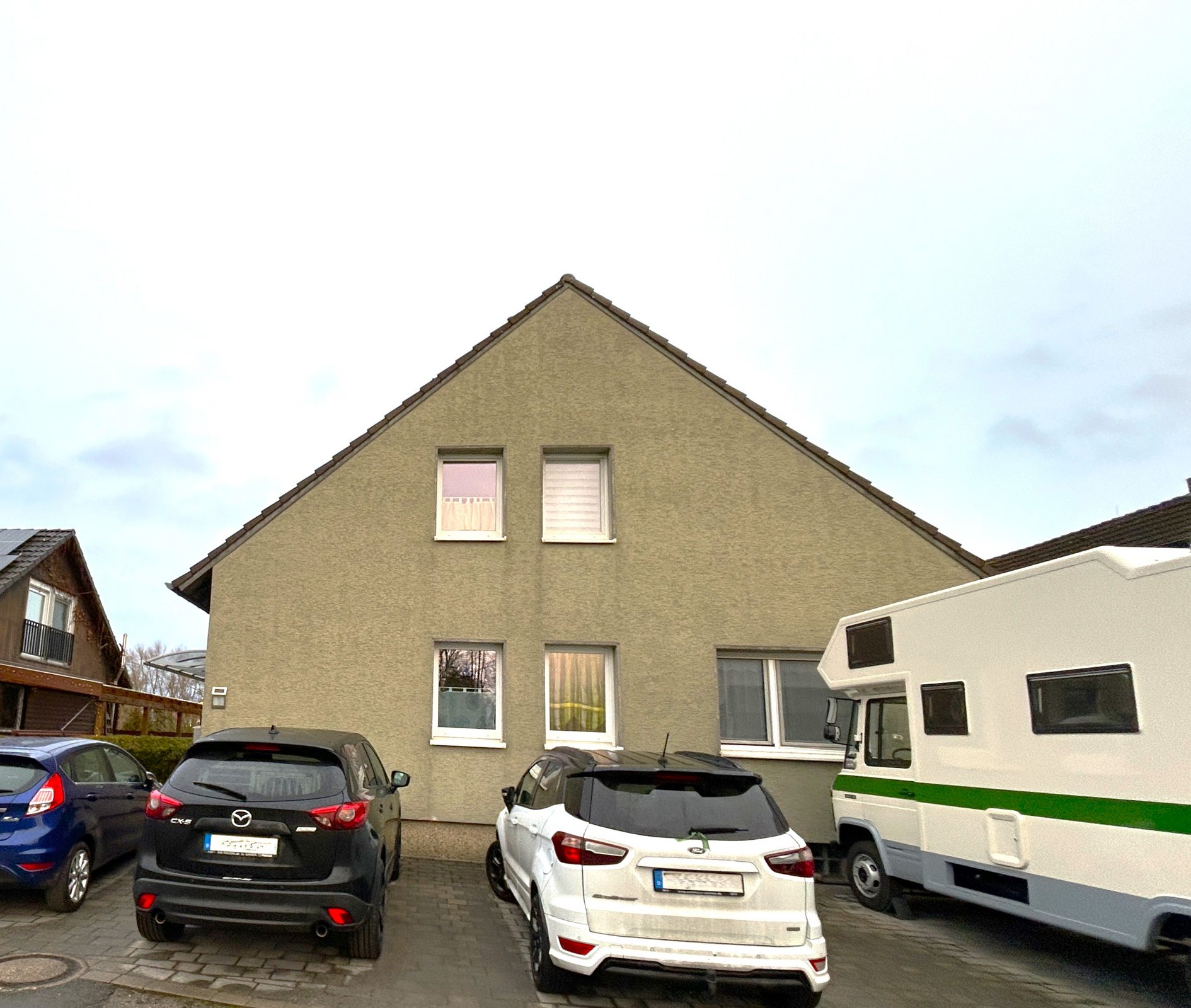 Wohnhausfront mit parkenden Autos und Wohnmobil