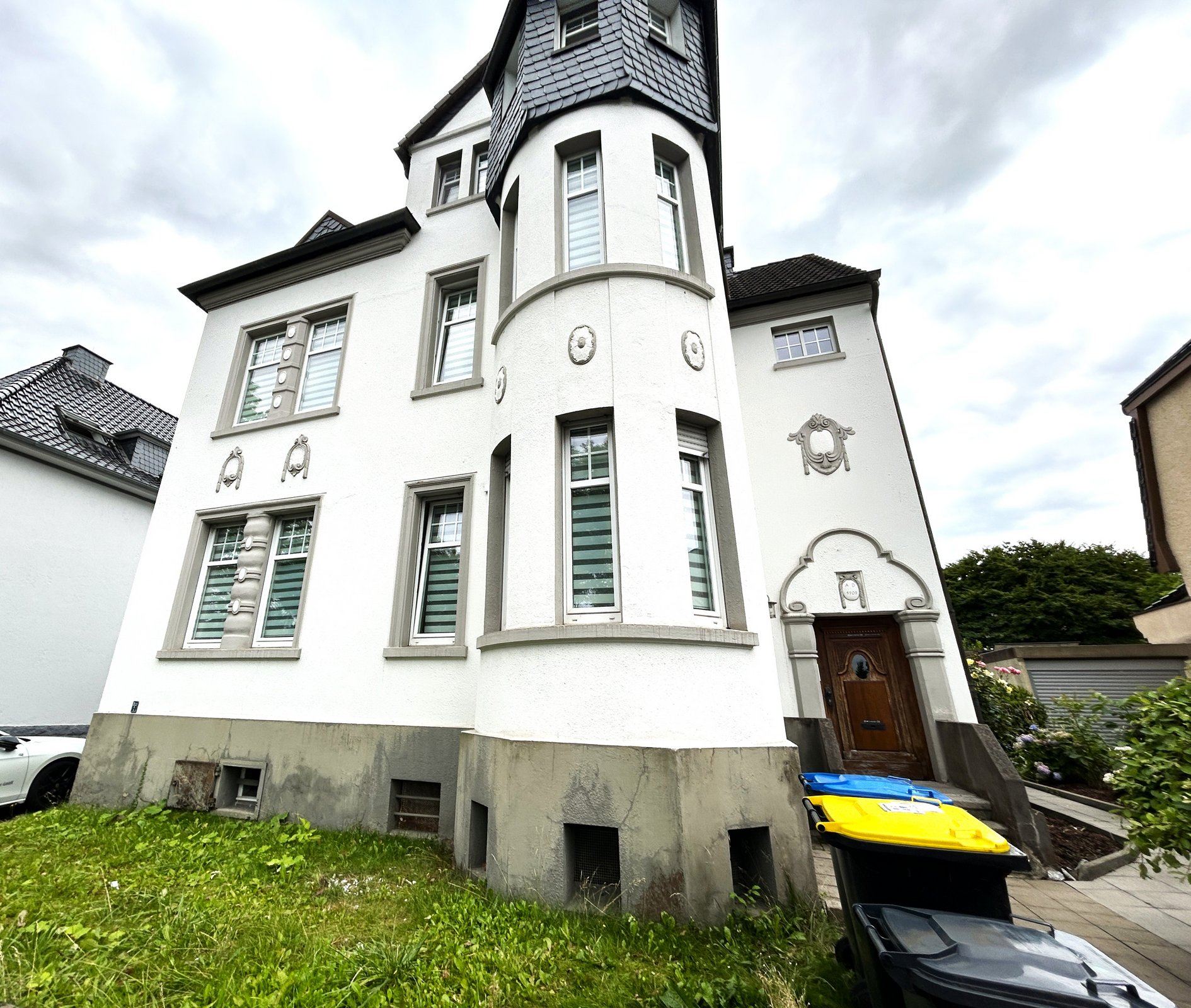 Weißes Wohnhaus mit Erkerturm und dekorativen Fassadenelementen