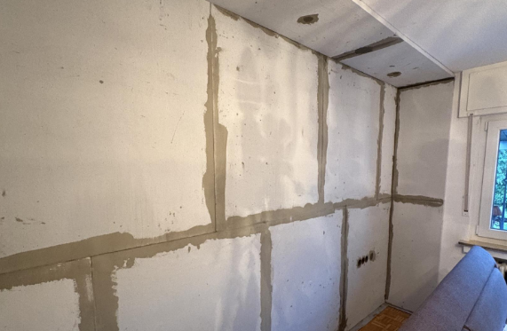 Wand mit grauer Masse an Fugen in einem Zimmer