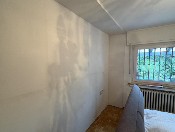 Helle Zimmerwand mit großflächigen Flecken neben Fenster