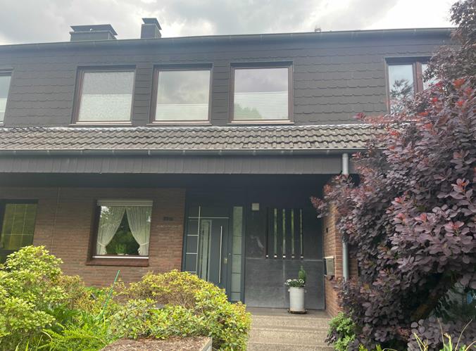 Reihenhaus mit dunkler Dachfassade, überdachtem Eingang und Vorgarten