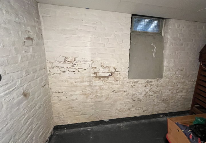 Abgeplatzte und verfärbte Backsteinwand in Kellerraum