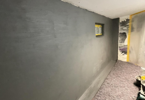 Dunkelgraue beschichtete Kellerwand in schmalem Raum