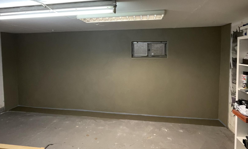 Glatte beschichtete Kellerwand mit kleinem Fenster in leerem Raum