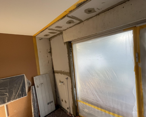 Abgeklebte Fensteröffnung mit Folie und freigelegtem Wandbereich im Zimmer