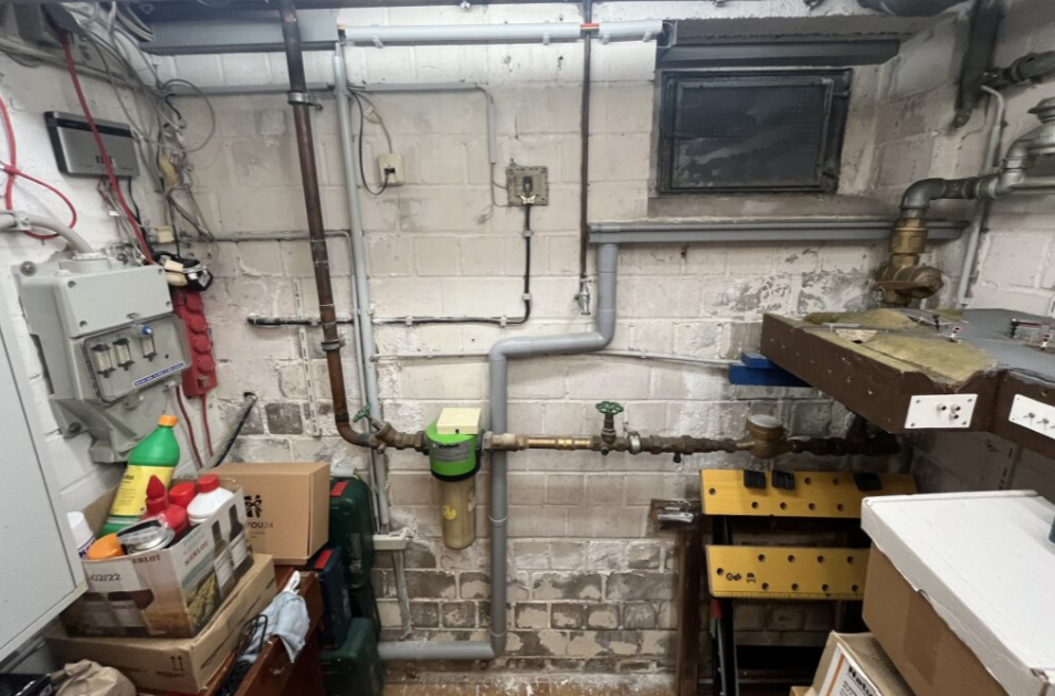 Kellerraum mit Rohrleitungen, Mauerwerk und elektrischen Installationen