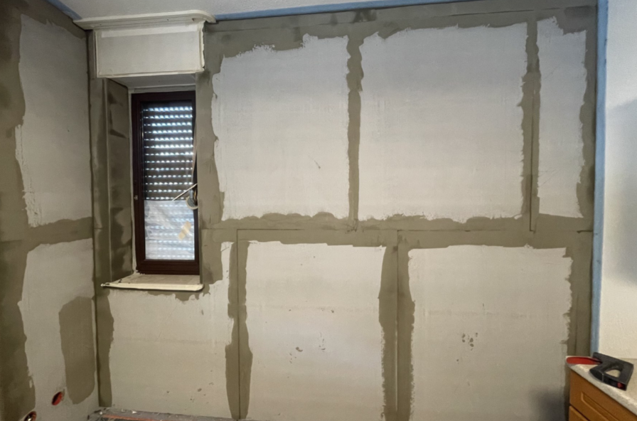 Helle Platten mit grauen Fugen an Wand neben Fenster