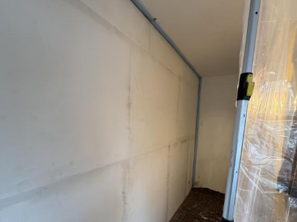 Helle Platten an schmaler Zimmerwand, Fugen und Metallprofile sichtbar