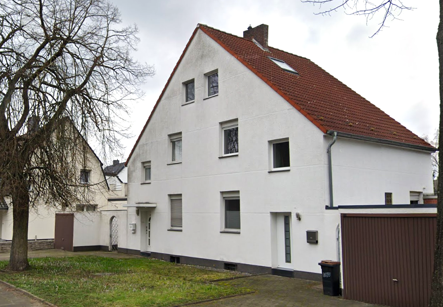 Weißes Wohnhaus mit rotem Ziegeldach und Garage, Straßenansicht