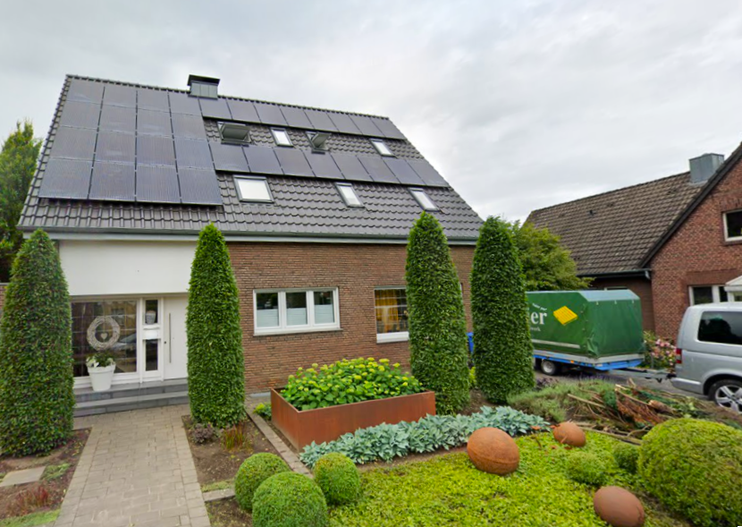 Einfamilienhaus mit Solaranlage auf dunklem Satteldach und gepflegtem Vorgarten