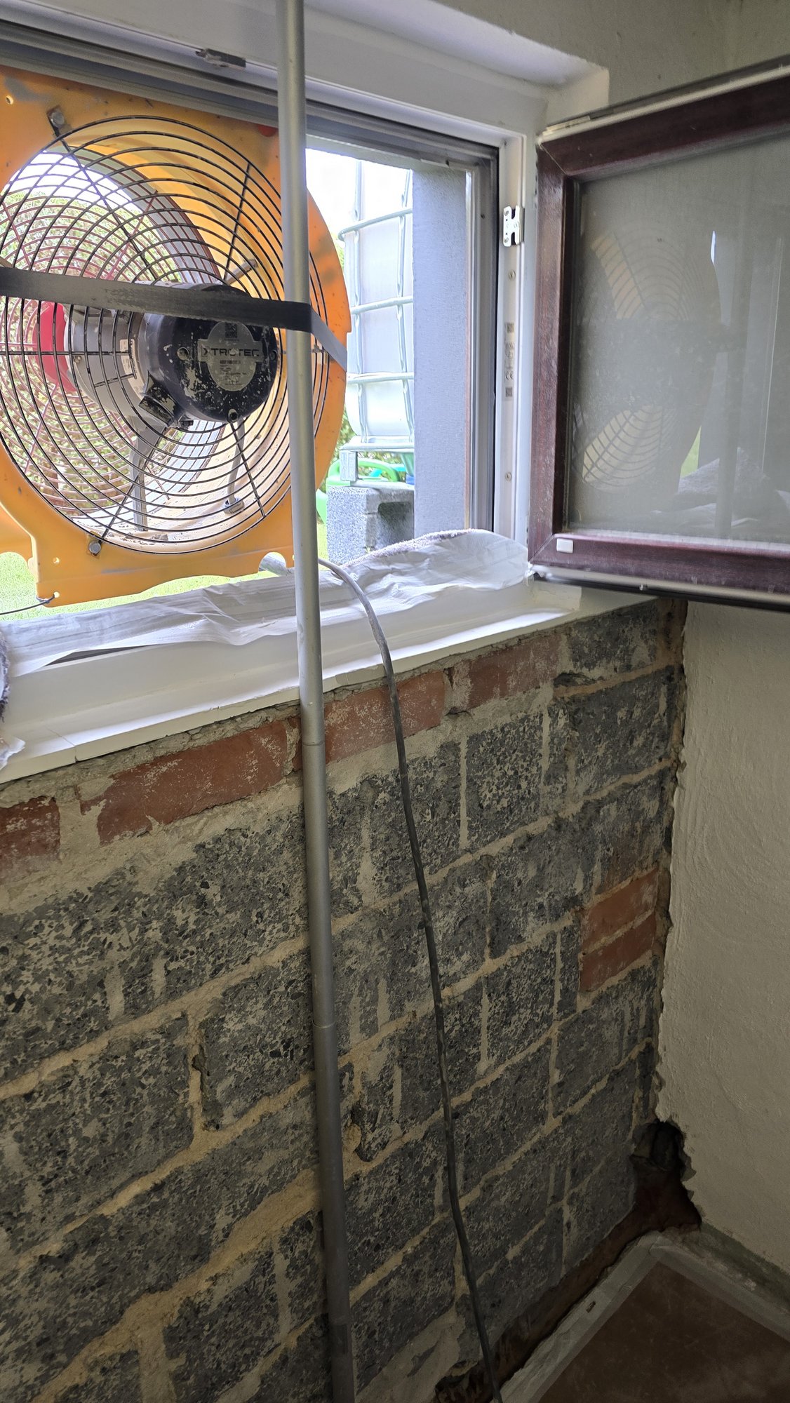 Gelber Ventilator im Fenster bringt den Staub gleich nach draußen während der Untergrundvorbereitung
