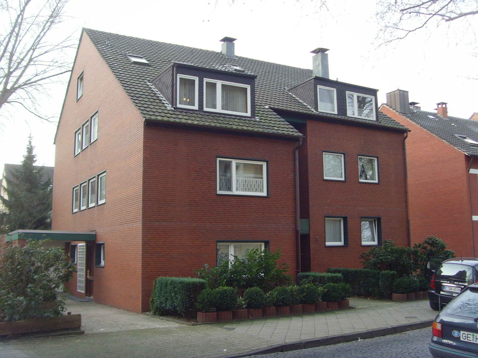 Mehrstöckiges Backsteinhaus mit Satteldach und Dachgauben, Straßenansicht.