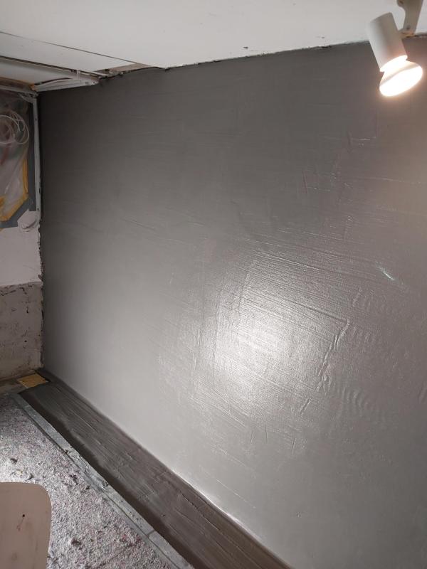 Glatte graue Masse auf Kellerwand, Innenraum mit Deckenleuchte