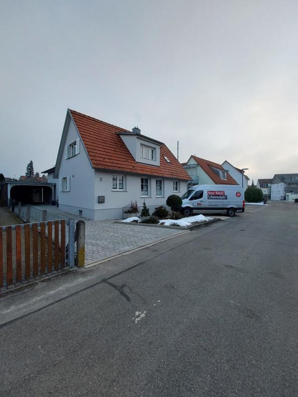 Einfamilienhaus an Wohnstraße mit geparktem Transporter vor dem Eingang
