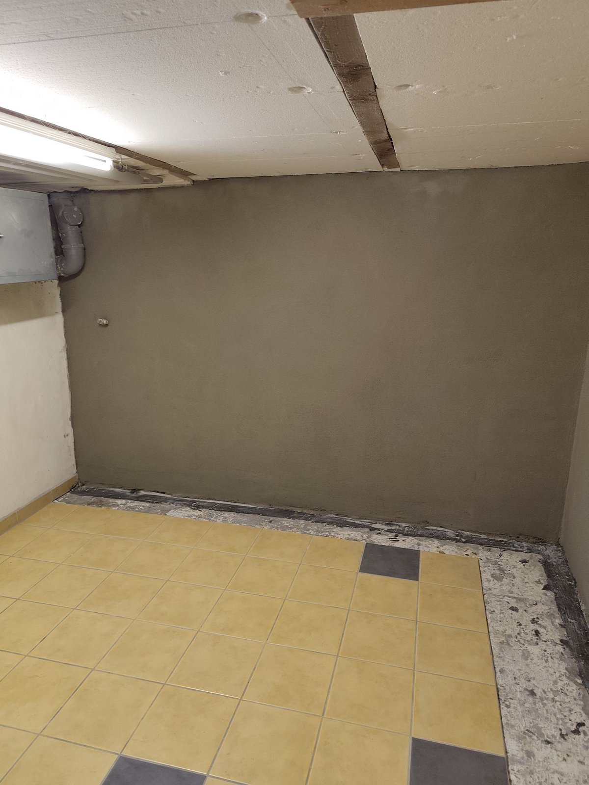 Glatter grauer Wandabschnitt in gekacheltem Kellerraum