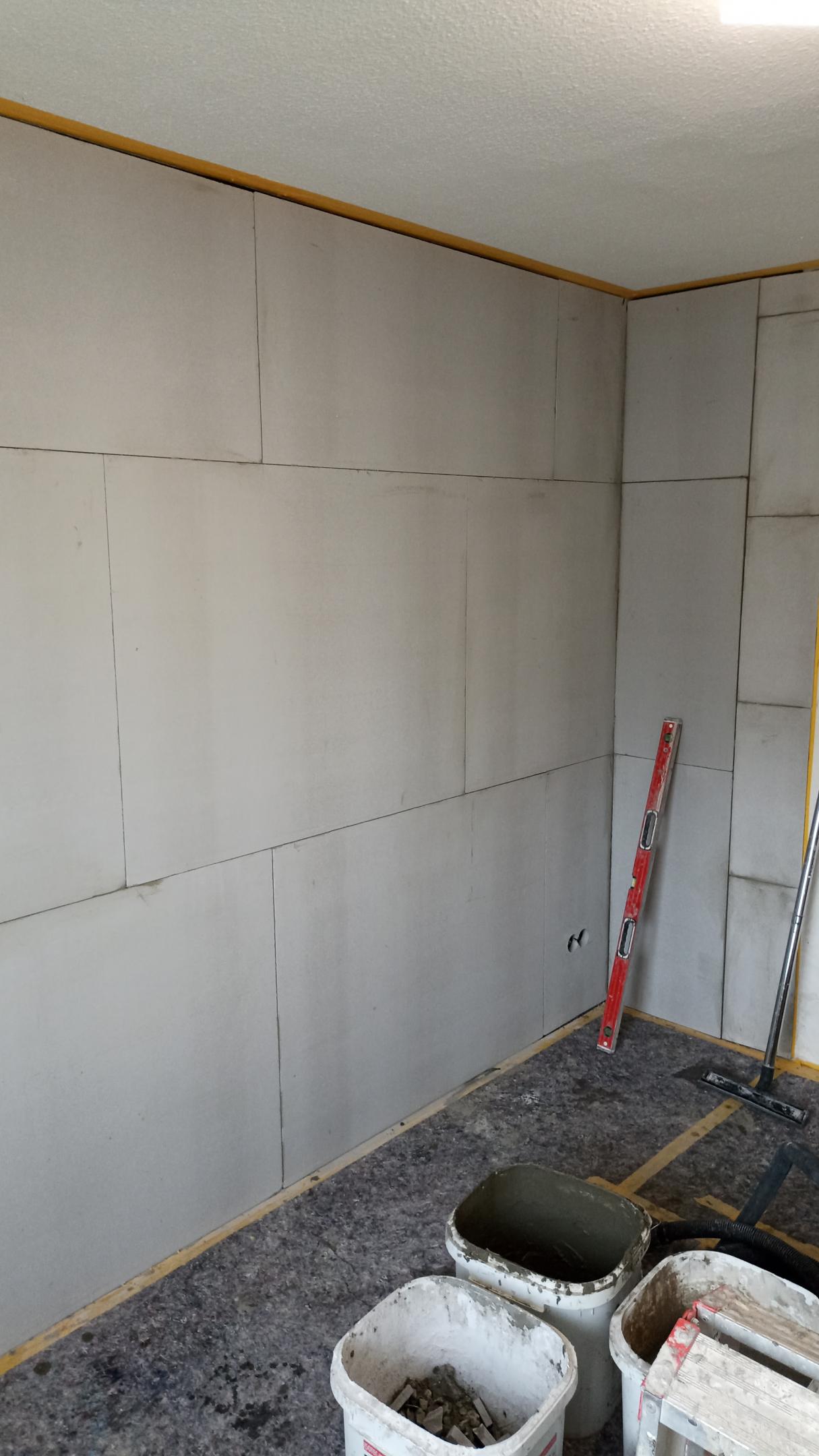 Helle Platten an Zimmerwand montiert, Renovierung mit Wasserwaage und Eimern