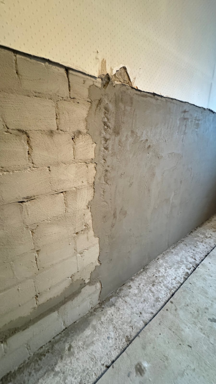 Teilweise verputzte Mauer aus hellen Steinen im Innenraum