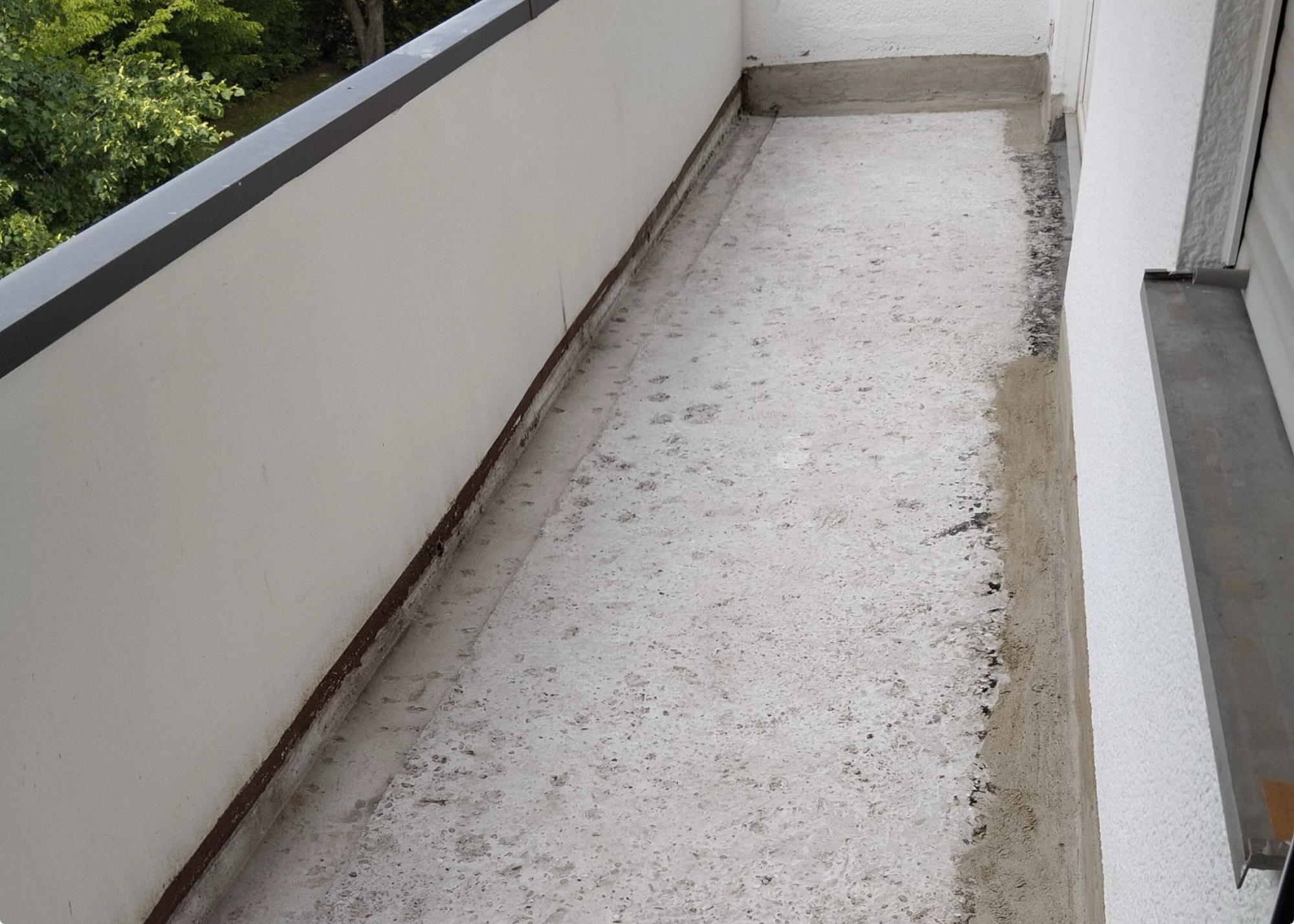 Rohbetonboden auf schmalem Balkon, Randanschlüsse mit grauer Masse bearbeitet