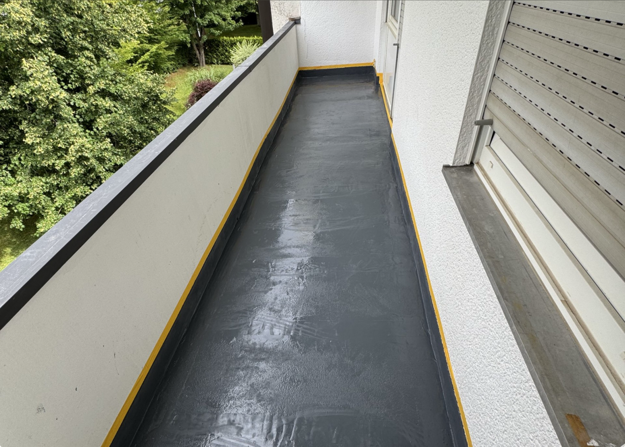 Balkonboden mit schwarzer Beschichtung und gelben Randstreifen