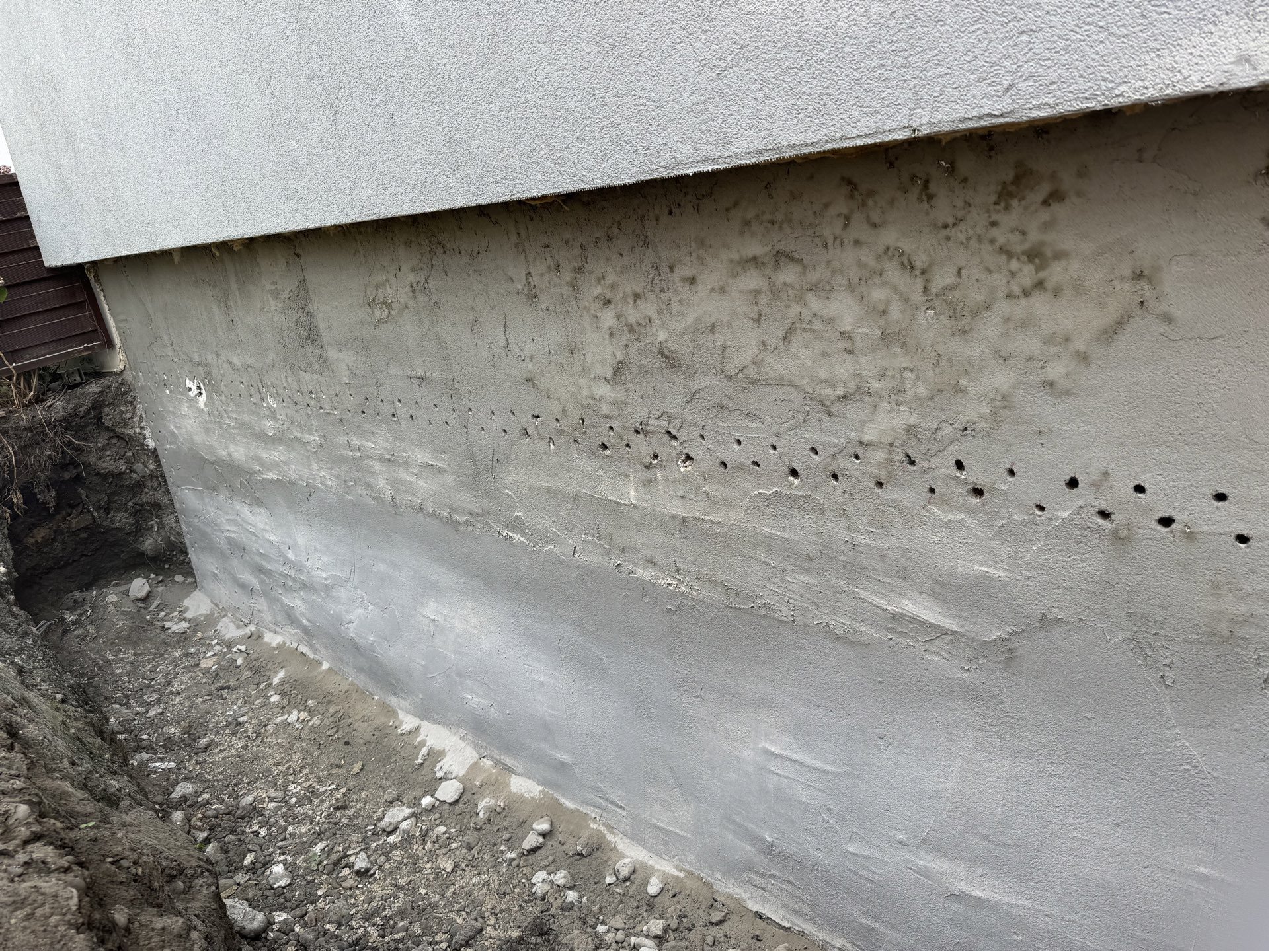 Reihe gebohrter Löcher in freigelegter Gebäudeaußenwand