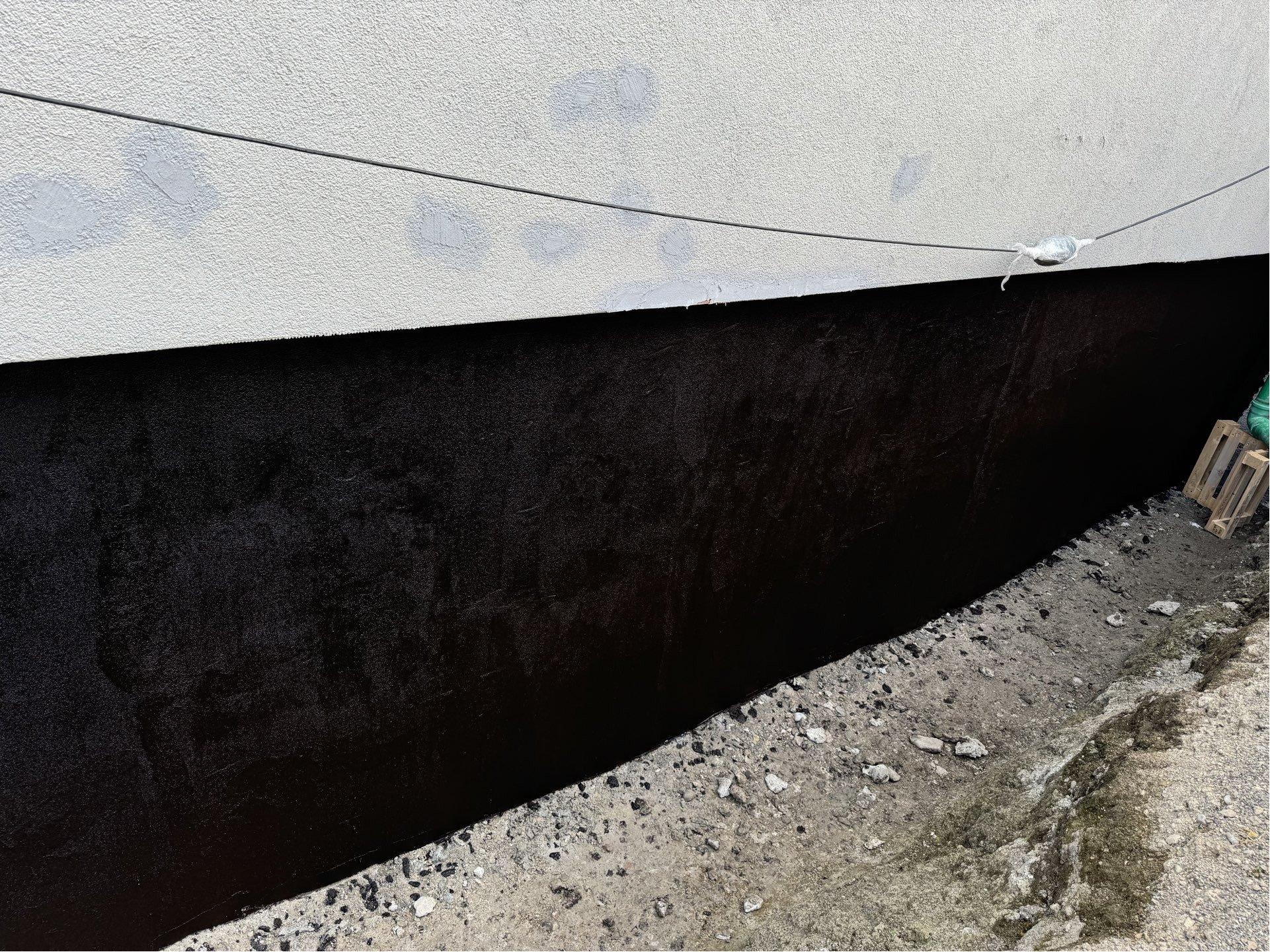 Schwarze Masse auf Kellerwand im Außenbereich