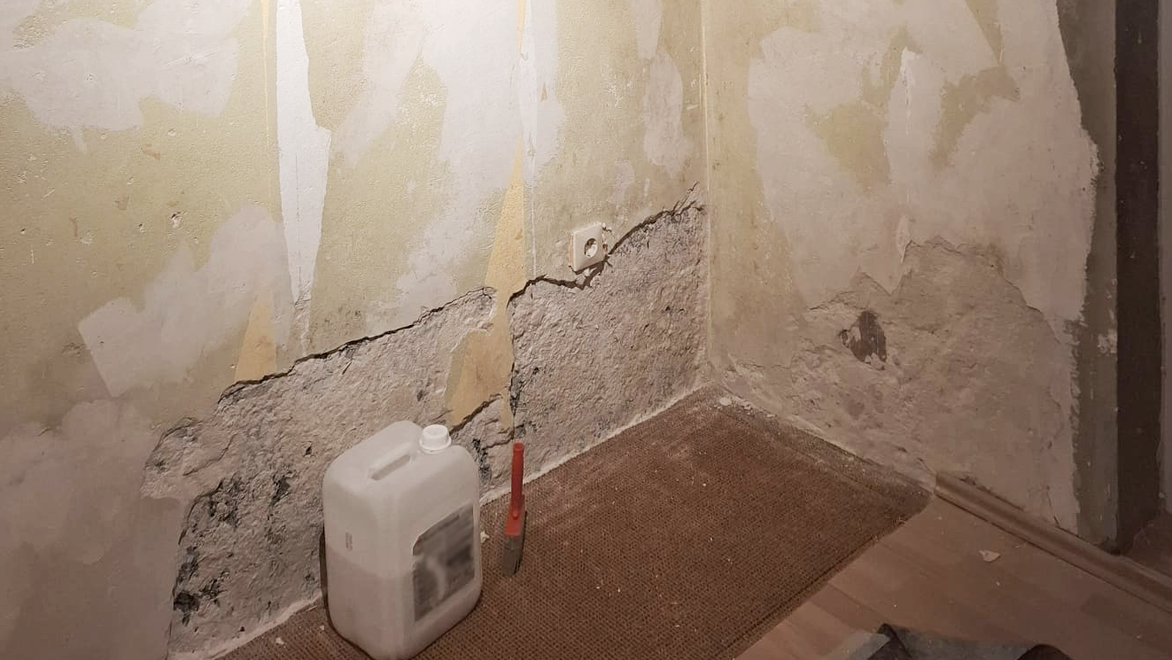 Abgeplatzte Wandfläche mit freiliegender rauer Masse in der Raumecke