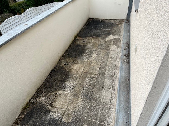 Verschmutzter Balkonboden mit grauen Platten und dunklen Ablagerungen, Schrägansicht