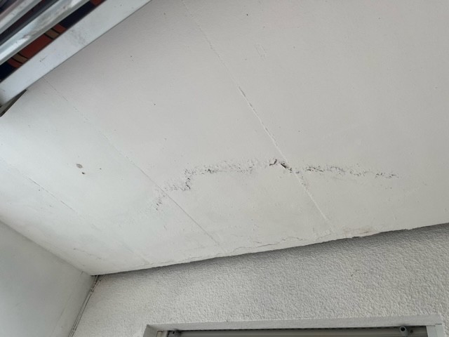 Dunkle Flecken und Risse an Zimmerdecke über Türrahmen, Nahaufnahme