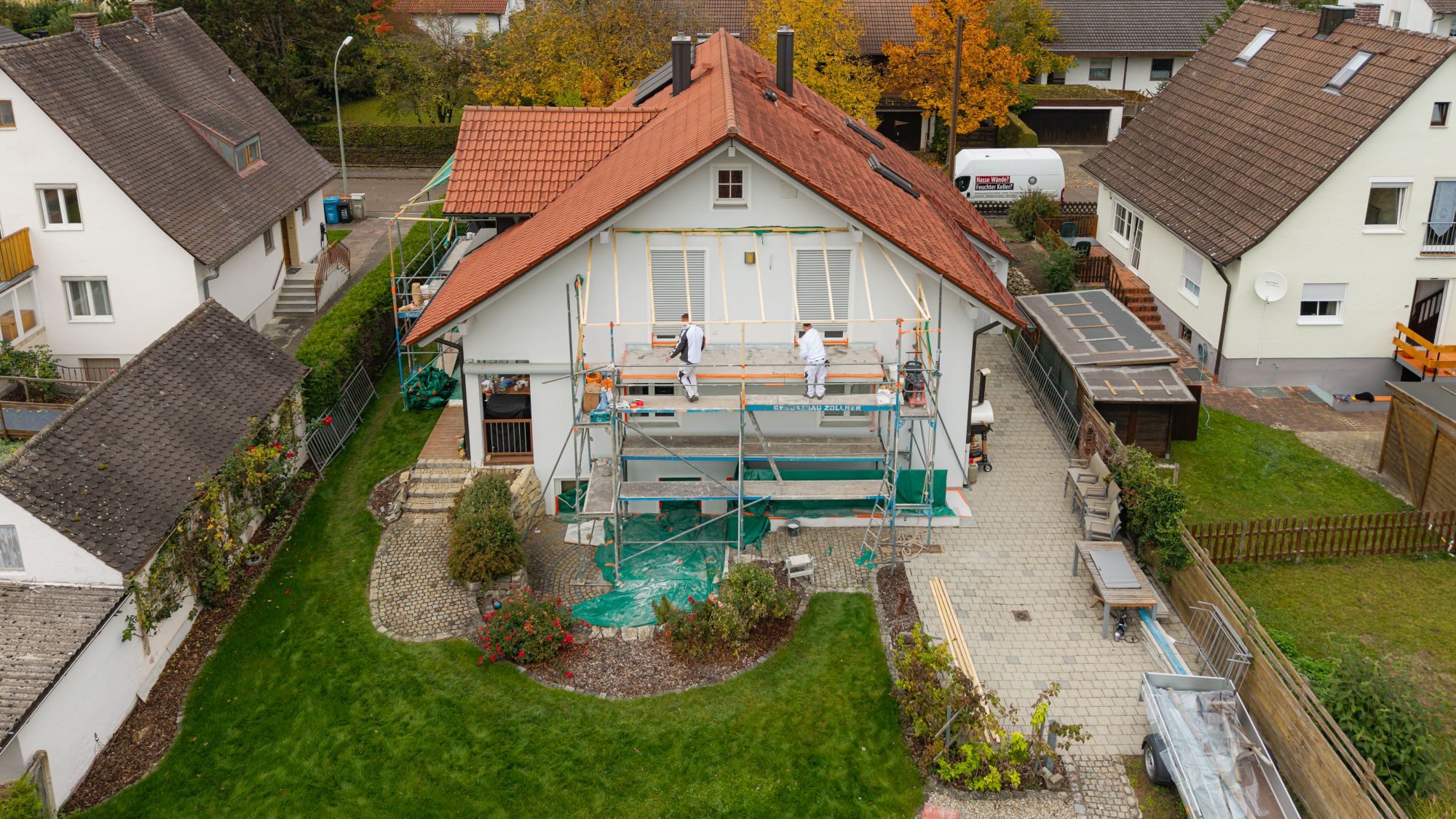 Zwei Arbeiter sanieren Hausfassade auf Geruest, Luftaufnahme