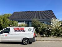 Weißer Transporter vor Einfamilienhaus mit blühenden Sträuchern