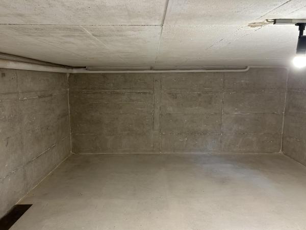 Leerer Kellerraum mit Betonwänden, Betonboden und Deckenrohr