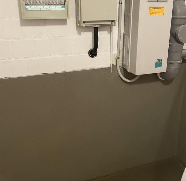 Kellerwand mit grauer Beschichtung und montierten Elektroverteilern, Nahaufnahme