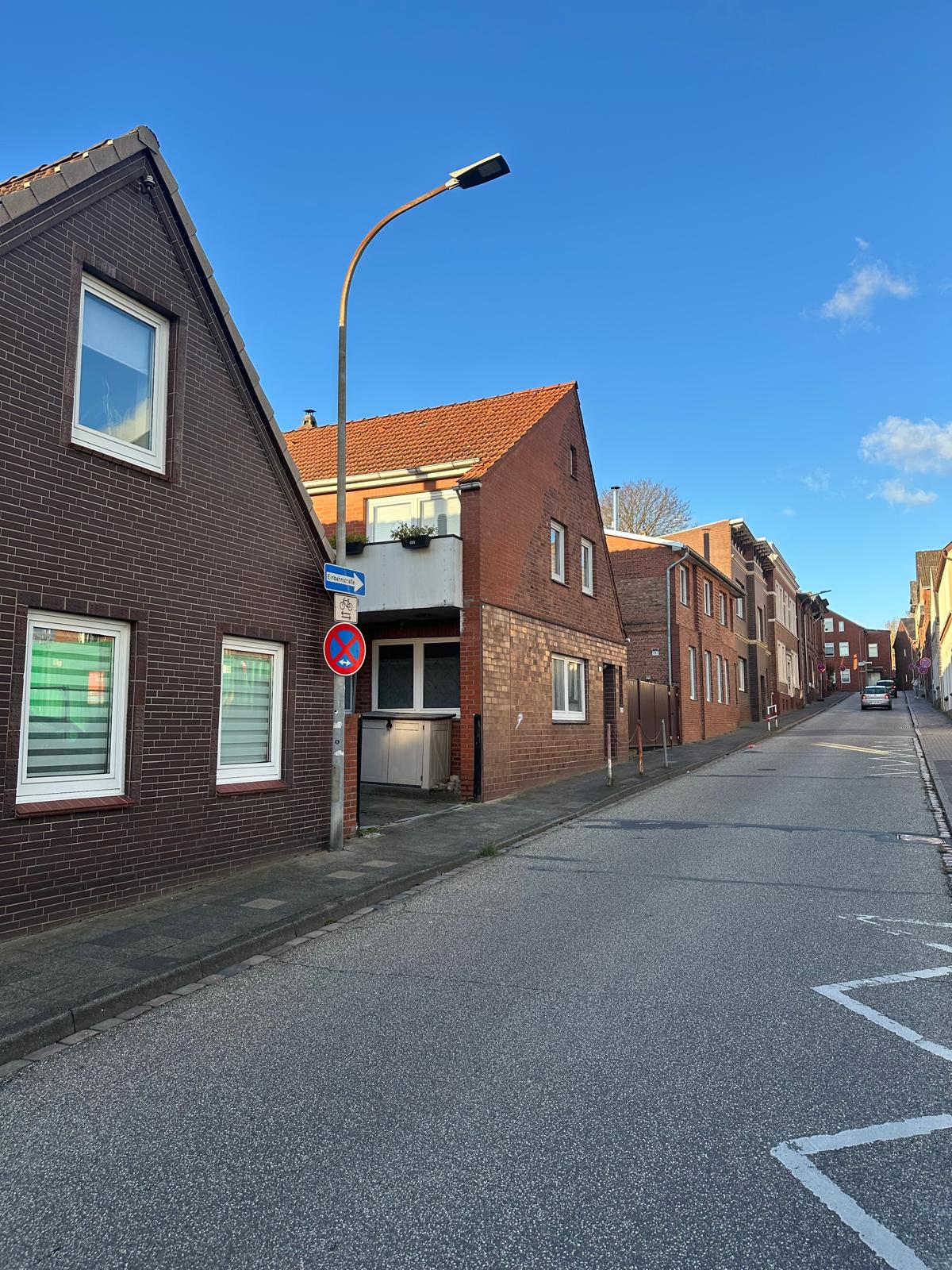 Ruhige Straße mit Backsteinhäusern und klarer blauer Himmel.