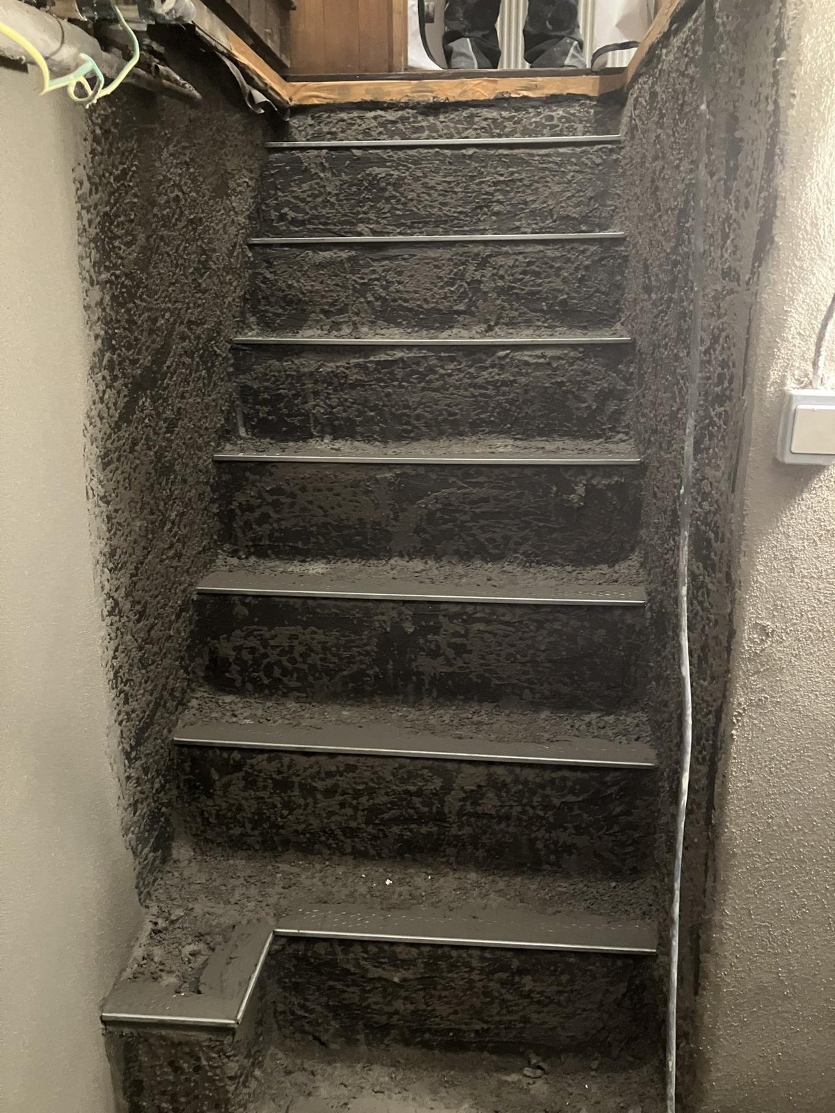 Mit dunkler Masse beschichtete Kellertreppe