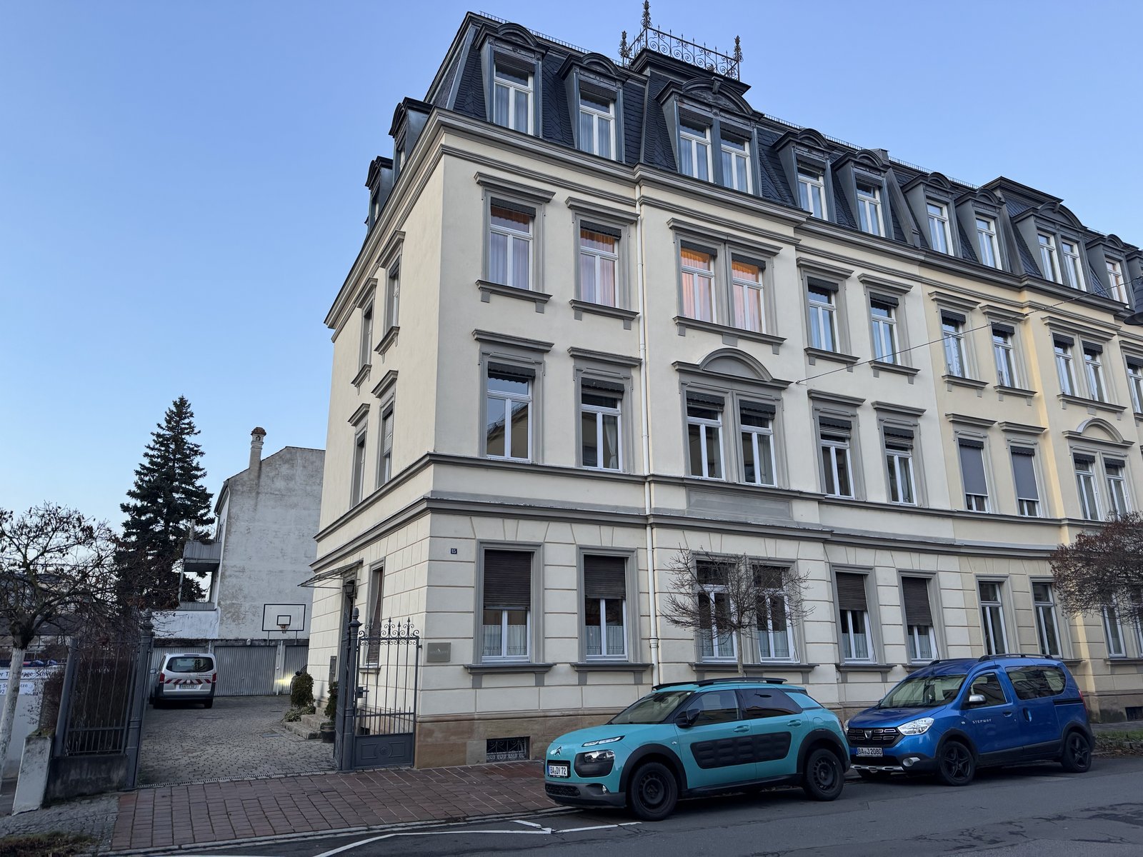 Mehrstöckiges Altbauwohnhaus an Straße mit parkenden Autos