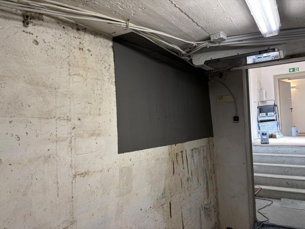 Schwarze Masse auf Kellerwand aufgetragen, Technikraum mit Leitungen