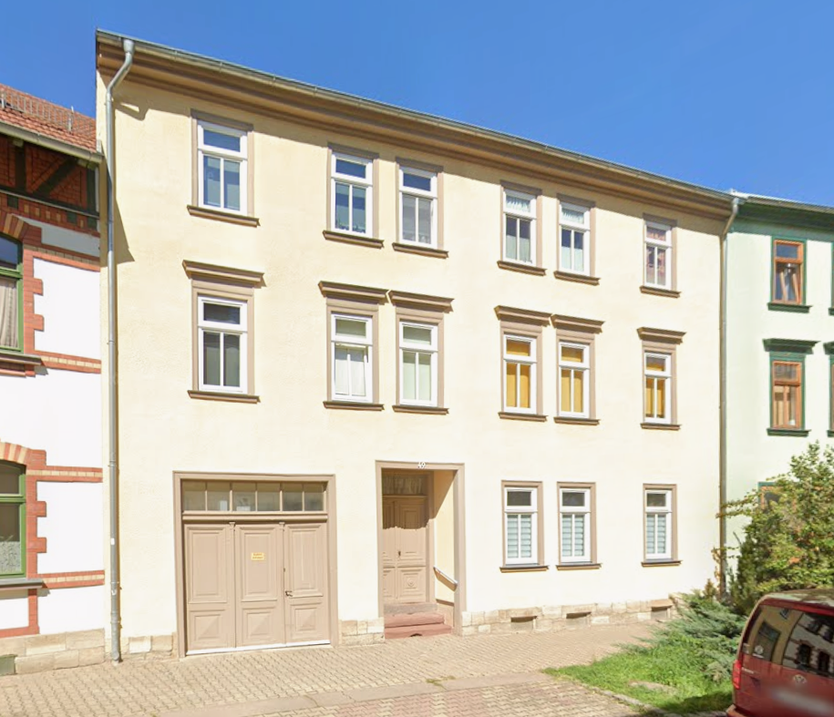 Helle Wohnhausfassade mit mehreren Fenstern, Eingang und Garagentor